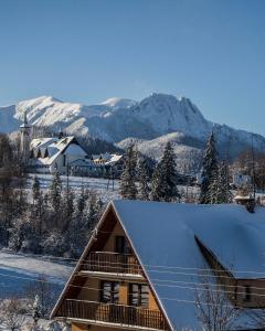 a house covered in snow with mountains in the background at Zwijaczówka in Zakopane