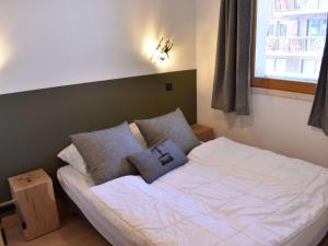 a bedroom with a bed with pillows and a window at Charmant T3 avec balcon, ascenseur et piscine en été, proche pistes et centre, idéal pour 6 pers. - FR-1-180-565 in Les Allues