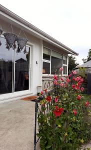 um guarda-chuva e flores em frente a uma casa em Stump Cottage em Christchurch