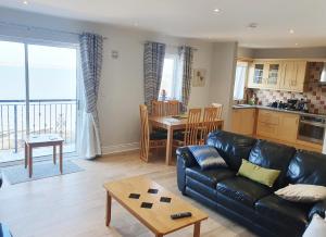 sala de estar con sofá de cuero negro y mesa en Ballycotton Holiday Apartment No 6 en Ballycotton