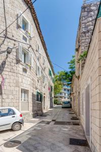 Une allée avec une voiture blanche garée à côté d'un bâtiment en pierre dans l'établissement Under Constructiion, à Split
