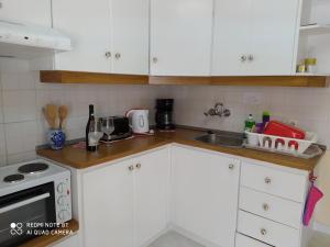 cocina con armarios blancos y encimera en Efi's Cottage by the sea en Fiskardho