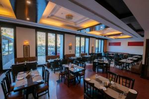 een restaurant met tafels, stoelen en ramen bij Mastiff Grand Manali Resort in Manāli