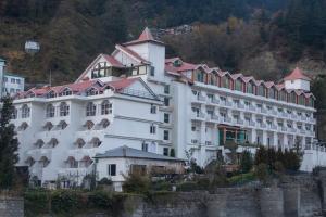 een groot wit gebouw met een rood dak bij Mastiff Grand Manali Resort in Manāli