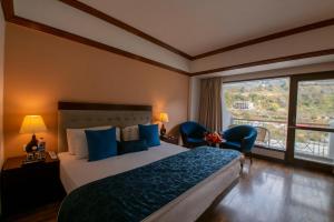 een slaapkamer met een groot bed en een groot raam bij Mastiff Grand Manali Resort in Manāli +70 foto's