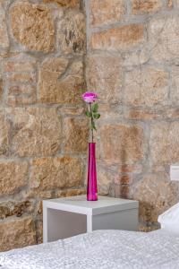 une fleur rose dans un vase assis sur une table dans l'établissement Under Constructiion, à Split