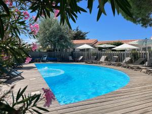 una piscina con sillas y una terraza de madera en La Villa - Hôtel Bien Être en Le Bois-Plage-en-Ré