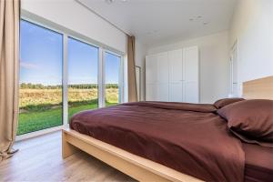 a bedroom with a large bed and a large window at 360 Apartments in Užpelkiai