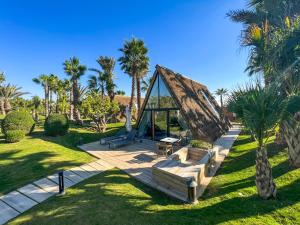 a triangular tent in a park with palm trees at Le Domaine Limoune in Oulad Teïma