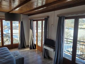 a living room with a tv and large windows at Les Jolis Coeurs in Thiéfosse