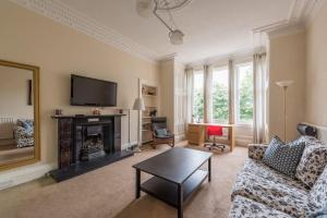 a living room with a fireplace and a tv at Beautiful 2 Bed 2 Bath Flat overlooking Meadows Park in Edinburgh