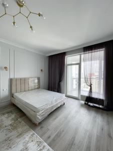 a bedroom with a bed and a large window at Premium Apartments Esil Riverside in Astana