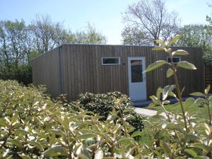 a small shed with a white door in a garden at Strandstudio Cato, vlakbij zee! in Callantsoog