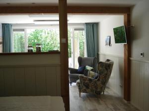 a living room with a couch and a chair and a window at Strandstudio Cato, vlakbij zee! in Callantsoog