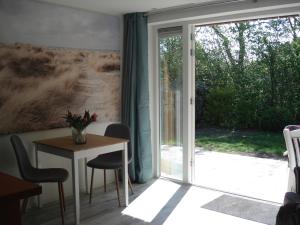 a room with a table and a sliding glass door at Strandstudio Cato, vlakbij zee! in Callantsoog