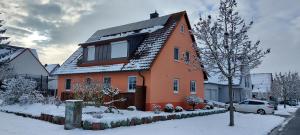 a orange house with snow on the ground at Ferienwohnung Niedermeyer in Röthlein