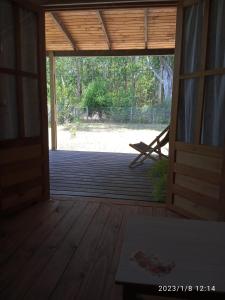 una puerta abierta a un porche cubierto con una silla en La Cabaña, en Sauce de Portezuelo