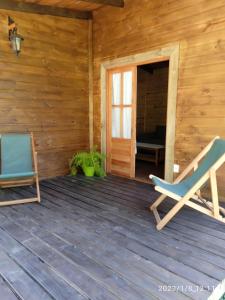 un porche de una cabaña de madera con una silla y una puerta en La Cabaña, en Sauce de Portezuelo
