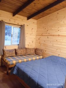 1 dormitorio con 1 cama en una habitación de madera en La Cabaña, en Sauce de Portezuelo