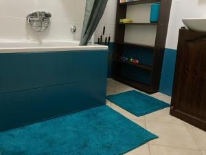 a bathroom with blue rugs and a tub and a sink at Pálmaház in Budapest