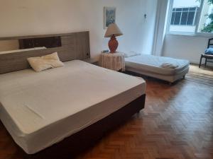 a bedroom with two beds and a table with a lamp at Apto 5 quartos na Orla de Copacabana in Rio de Janeiro
