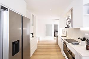 a kitchen with white cabinets and a stainless steel refrigerator at Amarela 17 in Tavira