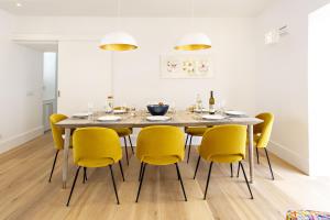 a dining room with a table and yellow chairs at Amarela 17 in Tavira