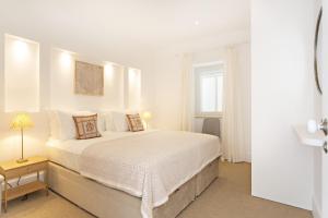 a white bedroom with a bed and a window at Amarela 17 in Tavira