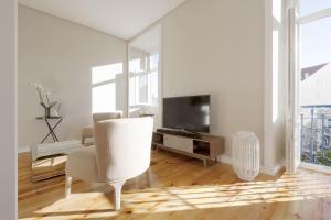 a white living room with a chair and a television at Apartamento Andrade in Lisbon