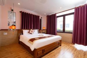 a bedroom with a large bed with red curtains at Hoa My II Hotel - Hoianese Old Town Hotel in Hoi An