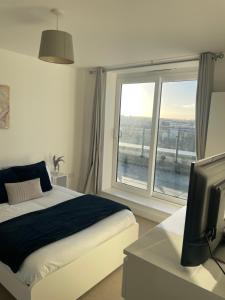 sypialnia z łóżkiem, telewizorem i oknem w obiekcie Business & Leisure Stays in RG2 - Top Floor Apartment with Balcony & FREE Parking! w mieście Reading