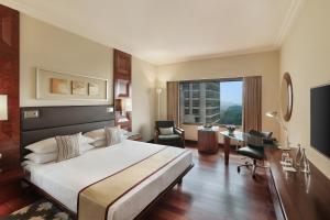 um quarto de hotel com uma cama grande e uma secretária em Hyatt Regency Delhi em Nova Deli