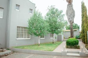 una casa bianca con degli alberi di fronte di Private luxurious 3 bedroom complete house a Bloemfontein