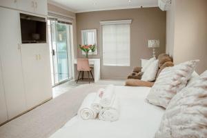 Private luxurious 3 bedroom complete house في بلومفونتين: سرير أبيض عليه مناشف في غرفة معيشة