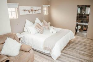 1 dormitorio con cama blanca con almohadas y sofá en Private luxurious 3 bedroom complete house, en Bloemfontein