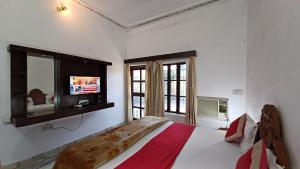 - une chambre avec un lit et une télévision murale dans l'établissement Green Park Resort, à Pushkar