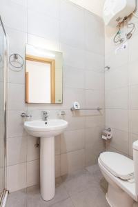 een badkamer met een wastafel, een toilet en een spiegel bij Corner view apartment in St Paul's Bay