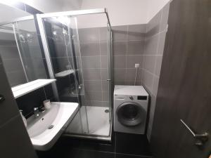 a bathroom with a shower and a sink and a washing machine at Luxusní apartmán Rezidence 1351 in Pardubice