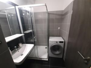 a bathroom with a shower and a sink and a washing machine at Luxusní apartmán Rezidence 1351 in Pardubice +7 photos