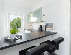 a kitchen with a black counter and stools at Sunset 24 Seetempel Scharbeutz in Scharbeutz