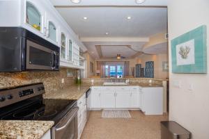 a large kitchen with white cabinets and a sink at Lawson Rock - Angelfish 101 condo in Roatán