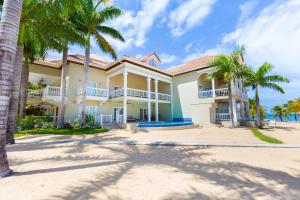 a large house on the beach with palm trees at Lawson Rock - Angelfish 101 condo in Roatán