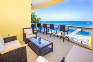 Un balcón con sillas y mesas y vistas al océano. en Del Playa #4 - 278851 Condo, en West End