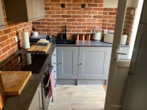a kitchen with white cabinets and a brick wall at One Long Entry with Terrace Bay View in Lyme Regis