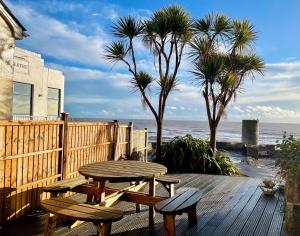 a wooden deck with a picnic table and palm trees at One Long Entry with Terrace Bay View in Lyme Regis