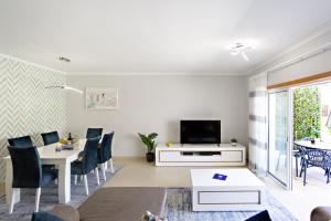 a living room with a television and a table and chairs at Fisherman 21 - Cabanas Beach in Cabanas de Tavira