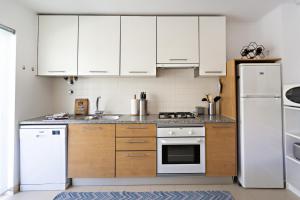 a kitchen with white cabinets and a white refrigerator at Fisherman 21 - Cabanas Beach in Cabanas de Tavira