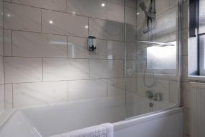 a white bathroom with a tub and a shower at Hazel House in West Bromwich