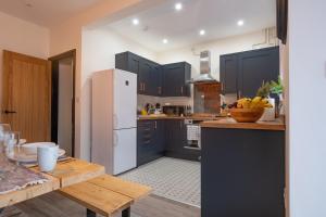 cocina con armarios azules y nevera blanca en Hazel House en West Bromwich