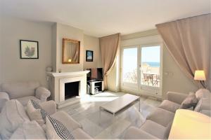 uma sala de estar com mobiliário branco e uma lareira em Townhouse TOBY em Estepona
